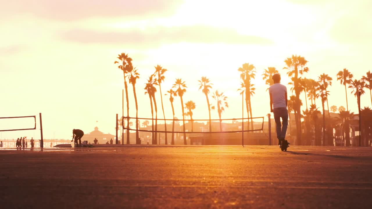 un hombre monta un scooter eléctrico hacia la puesta de sol