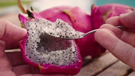 Comer-Fruta-Del-Dragón-Con-Una-Cuchara-Sobre-Una-Mesa-De-Madera-En-Un-Ambiente-Tropical-De-Verano