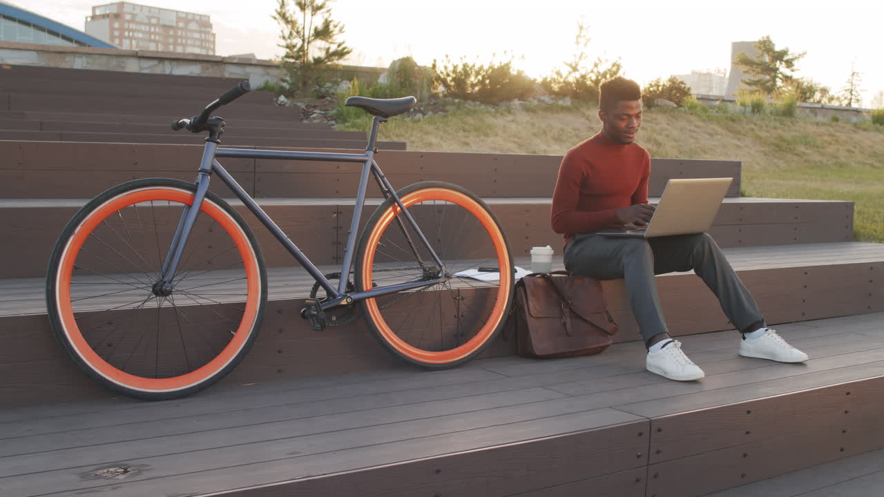 African American Man with Bike Working on Laptop in Park