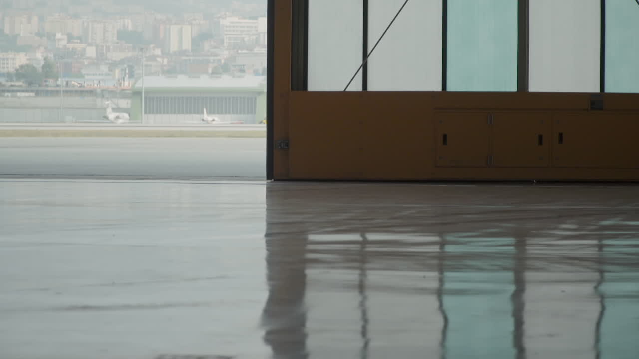 cierre de la enorme puerta del hangar del avión con grandes ventanas de vidrio, proyectando reflejos brillantes en el suelo epoxi cerca del campo de aterrizaje del aeropuerto en cámara lenta