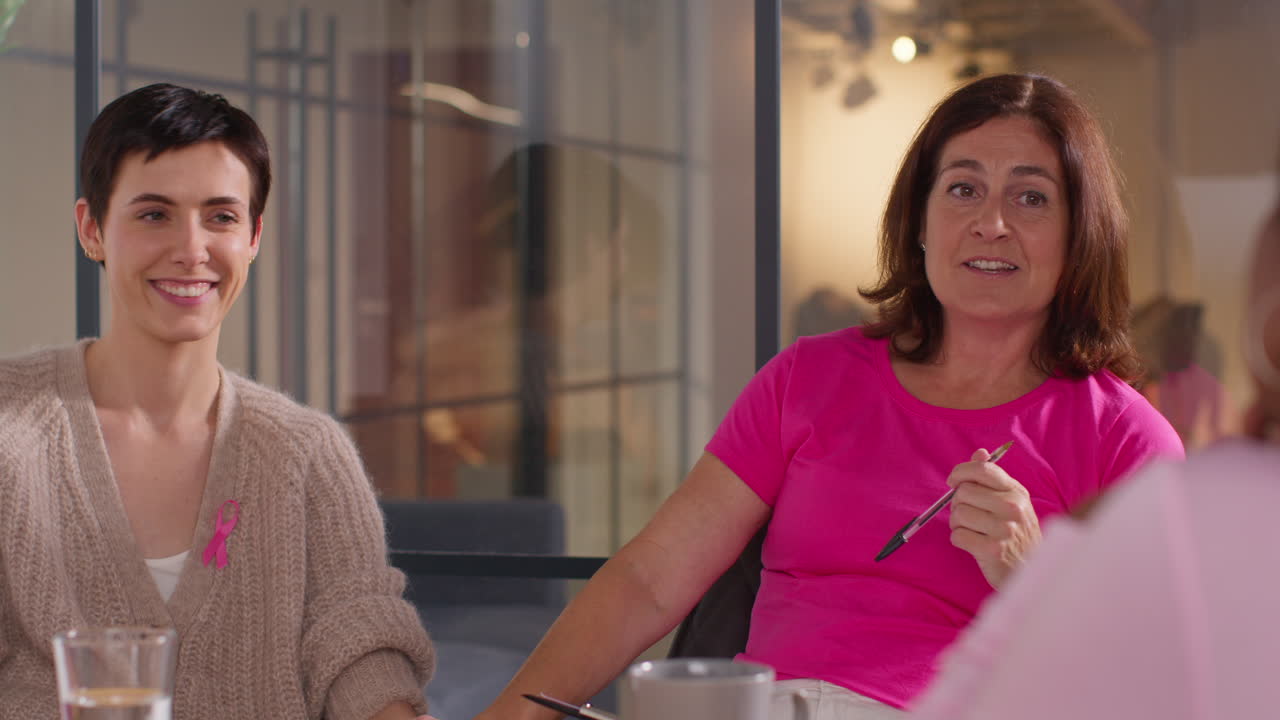 grupo de mujeres que llevan cintas rosas de concienciación sobre el cáncer de mama se reúnen y hablan en el grupo de apoyo a la terapia para pacientes con tratamiento de cáncer 4