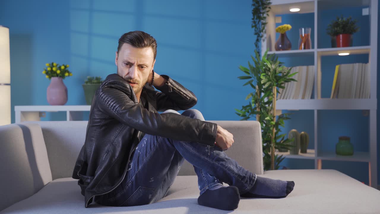 Giovane uomo frustrato seduto sul divano che si sente a disagio mentre riflette.