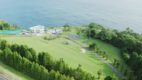 Top-down-drone-shot-of-a-Chopper-parked-in-the-middle-of-the-lawn-next-to-a-luxurious-villa-surrounded-by-lush-green-foliage