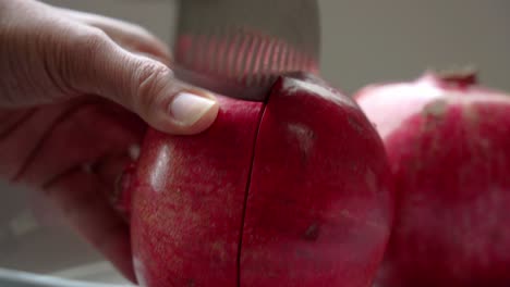 punto de vista cercano cuchillo cortando granada sentado en un plato blanco en la mesa antioxidantes saludables propiedades cardioprotectoras