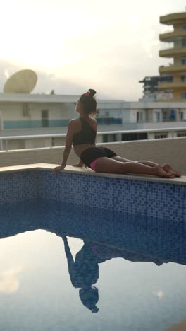 woman doing yoga on rooftop by pool at sunset