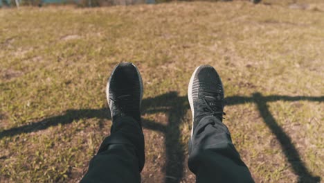 male legs with black and white sneakers swinging on top of the mountain