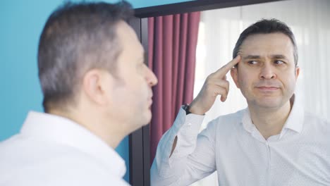 The-man-looking-at-the-wrinkles-on-his-face-in-the-mirror.