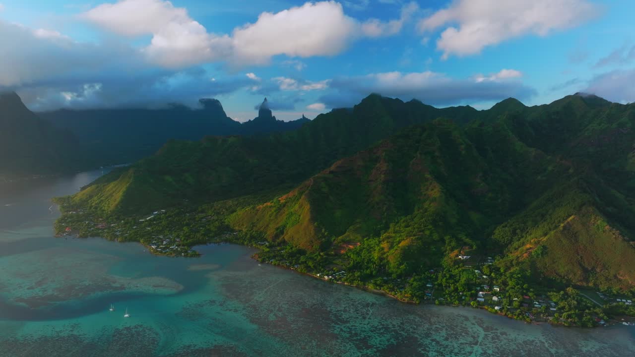 Golden hour sunset Cooks Opunohu Bay Moorea island French Polynesia aerial drone clouds covering Mount Mauaroa Tohivea Rotui clouds sailboats lagoon coral reef waves Pacific Ocean circle right