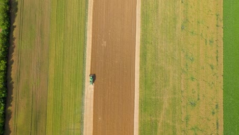 Top-Down-View-Of-Tractor-Working-In-Agriculture-Field-In-Summer---drone-shot