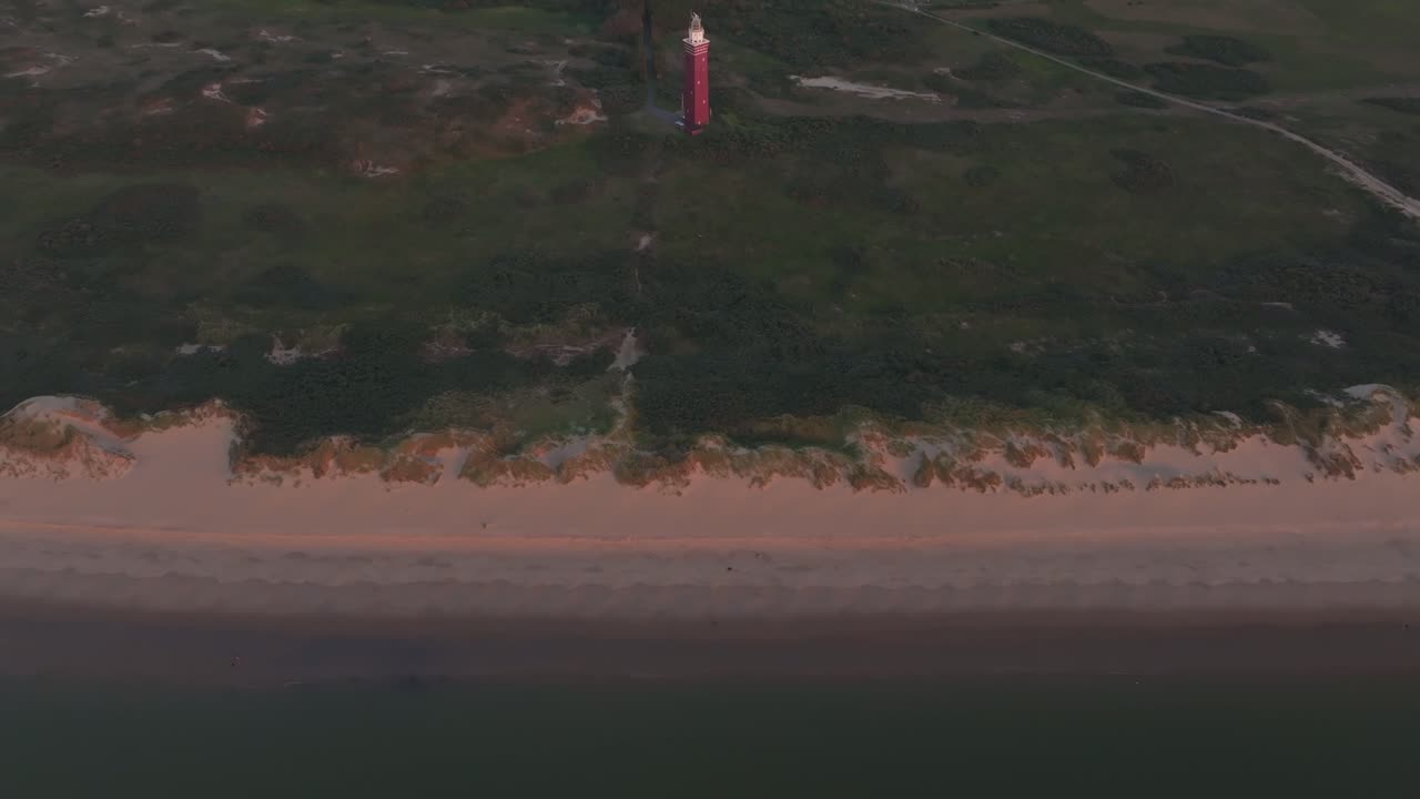 Vista aerea del faro di Westhoofd al tramonto con luce calda sulla spiaggia, sulle dune e sulla costa del Mare del Nord a Ouddorp.