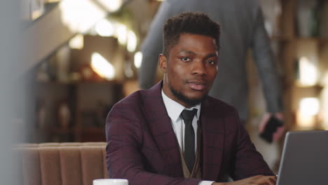 portrait of african american businessman with laptop in restaurant