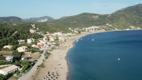 Toma-Aérea-De-Una-Playa-Mediterránea,-Justo-Debajo-De-Las-Verdes-Montañas-Cubiertas-De-Bosque