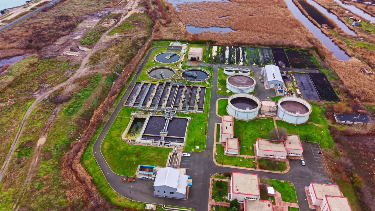Water treatment facility located in a rural area during daylight with various tanks and buildings shown in a green landscape