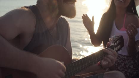 young man playing guitar on beach