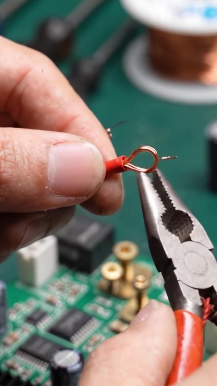 Precision Wiring: A Close-Up of Hand Safety Techniques in Electronics as a Technician Connects Copper Wires Using Pliers on a Circuit Board