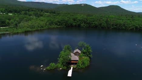 Drone-footage-of-serene-NH-White-Mountains-lake,-isolated-island-house,-and-natural-beauty