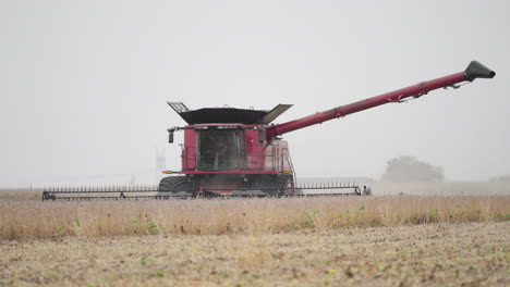 combine harvester gathering grain crops from a farm field on a dusty day