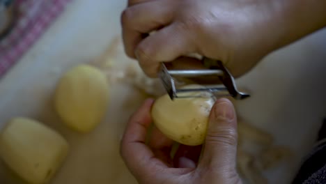 Vista-De-ángulo-Alto-De-Una-Persona-Pelando-Patatas-En-Casa