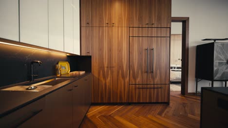 push-in-shot-inside-of-a-modern-dark-toned-kitchen-with-large-wooden-cabinets-and-appliances