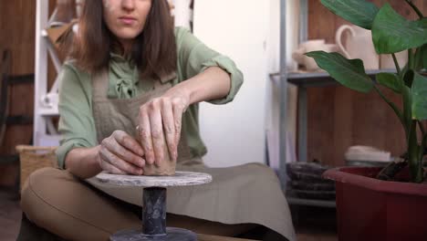la alfarera esculpe un pedazo de arcilla en una mesa. una mujer hace un objeto de cerámica. cerámica, artesanía y habilidades creativas en un estudio de arte. manos del maestro de primer plano.