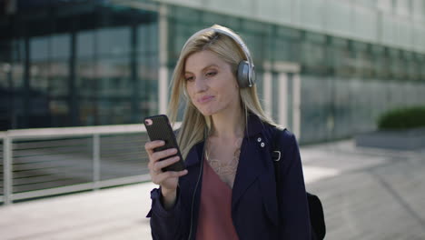 Retrato-De-Una-Joven-Y-Animada-Mujer-De-Negocios-Rubia-Que-Disfruta-Escuchando-Música-Usando-Audífonos-Enviando-Mensajes-De-Texto-Navegando-Por-Las-Redes-Sociales-Usando-Un-Teléfono-Inteligente