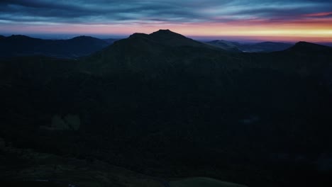 aerial forward at sunset, rays of golden light illuminate the valley during golden hour, auvergne - puy mary, france