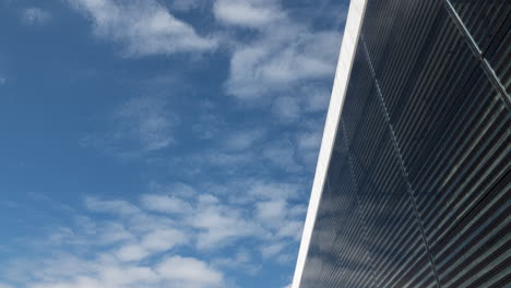 timelapse, clouds in sky pass above reflective glass of oslo opera house