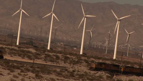 Dutch-angle-of-many-windmills-rotating-in-a-breeze-as-trains-pass-by