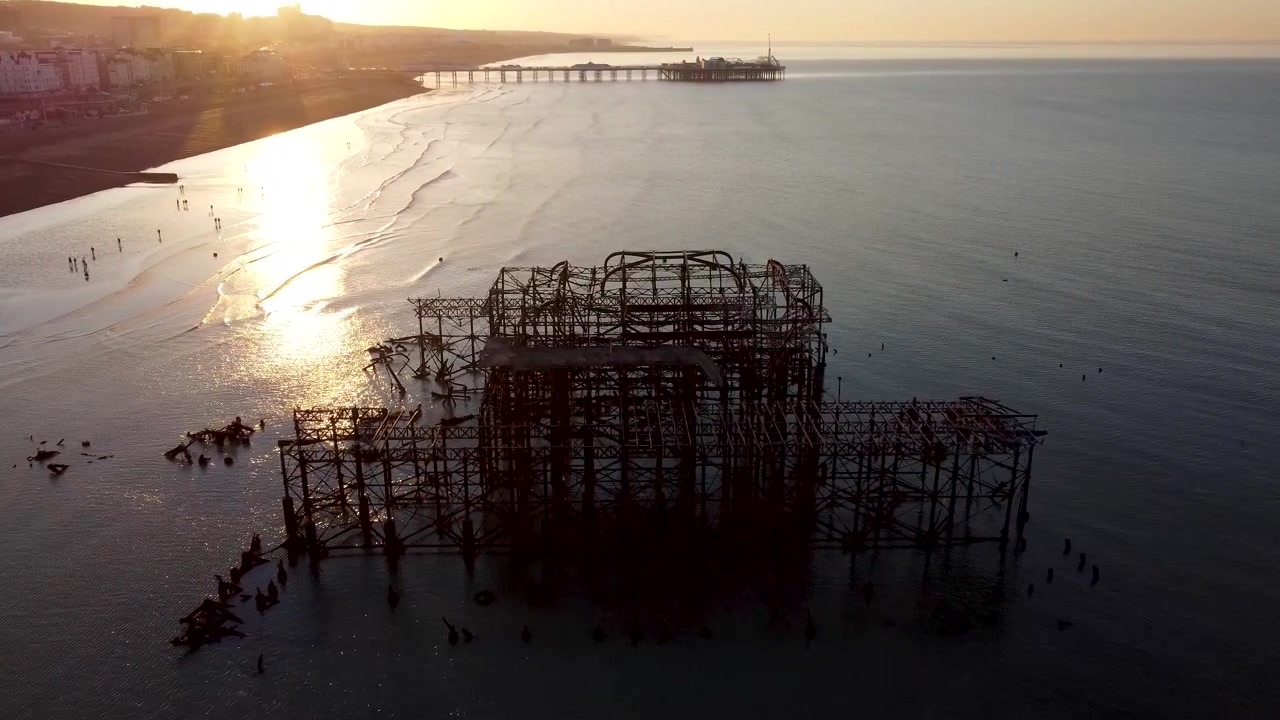 Drone shot approaching the ruins of the Brighton west pier in the sea, looking down over the pier as the shot passes over
