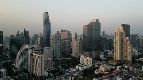 Bangkok's-impressive-skyline-on-a-clear-day,-stunning-aerial-footage,-Towering-skyscrapers-against-the-clear-blue-sky,-Unique-and-awe-inspiring-perspective-of-the-bustling-city