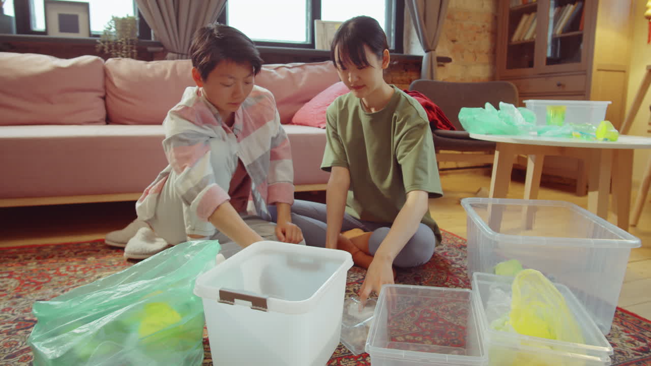 두 명의 아시아 여성이 집에서 쓰레기를 분류하고 있습니다.