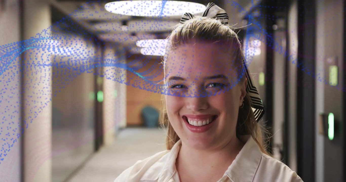 Donna in un corridoio aziendale sotto luci LED che sorride dopo che una sovrapposizione a spirale blu le attraversa il viso