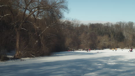 Scenic-winter-view-of-people-ice-skating-and-enjoying-the-sunny-day-in-Lhotka-Frozen-lake-in-Harasov,-Kokorin,-Czech-Republic---Wide-static-shot