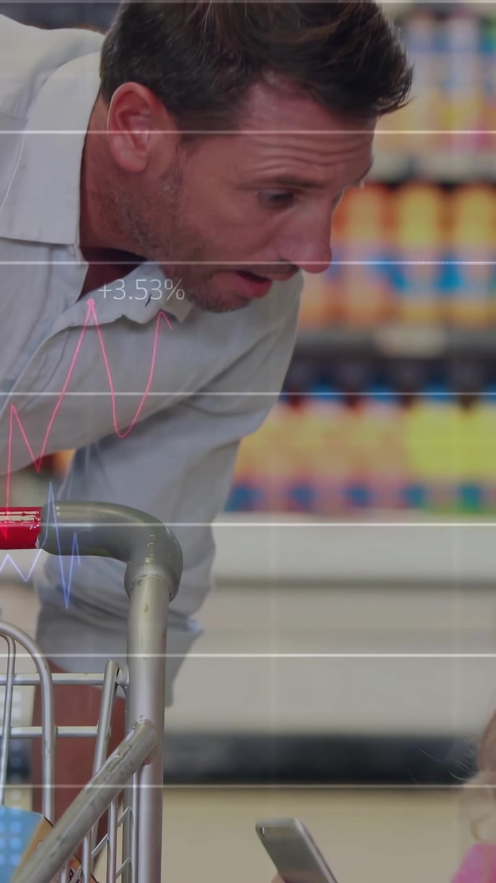 Vertical video: Adult male leaning over cart pointing, tapping girl's device while guiding purchase
