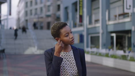 portrait of independent african american business woman wearing earphones listening to music waiting in city