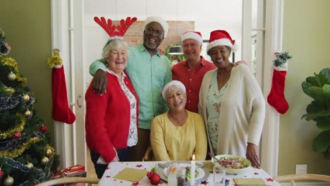 retrato de varios amigos mayores con sombreros de navidad abrazándose y sonriendo en la mesa de la cena de navidad