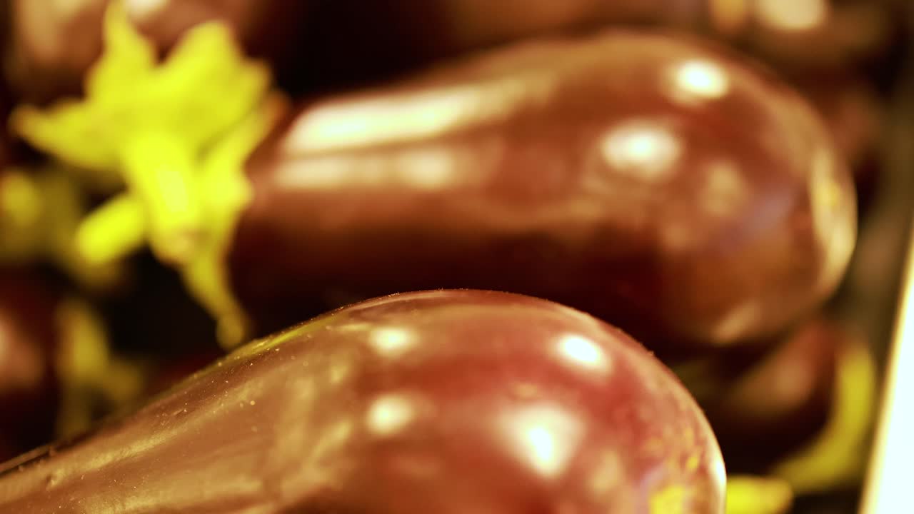Close-up shots of fresh eggplants with vibrant lighting, highlighting their glossy texture in a market setting
