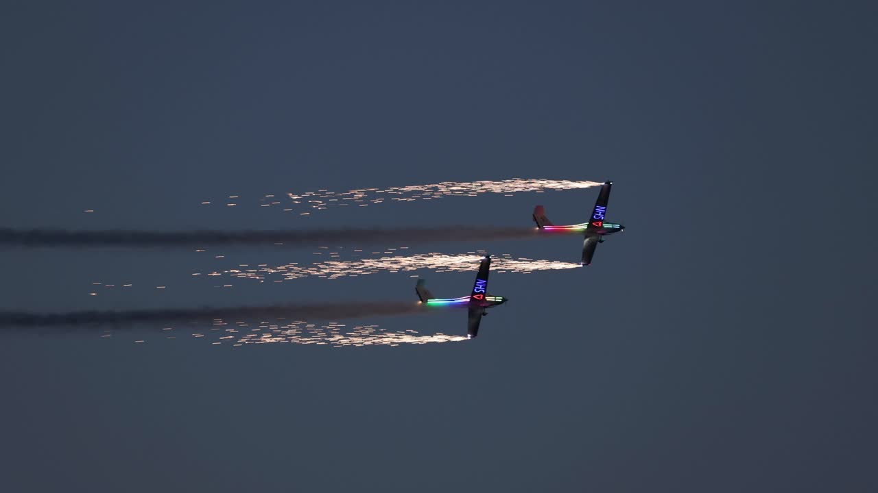 Tandem pyrotechnical aircraft doing tight maneuvers together whilst letting off fireworks