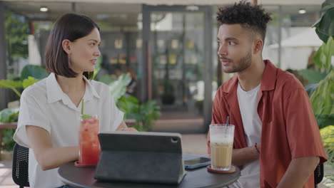 coworkers using digital tablet in outdoor cafe