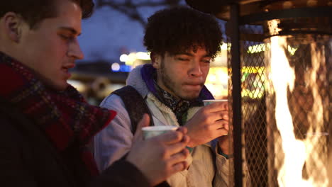 amigos hombres bebiendo vino caliente en el mercado de navidad