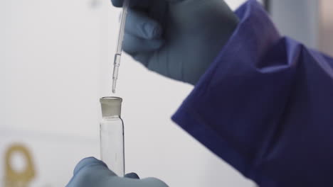 scientist using eye dropper to drip water into test tube