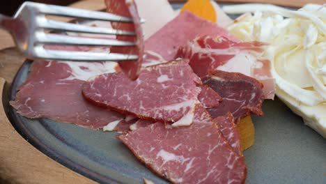 close-up of a plate of thinly sliced meat with a fork