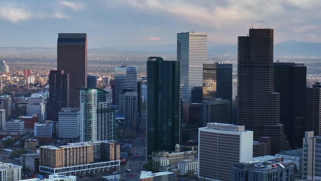 Downtown Denver cityscape city tall skyscraper buildings aerial drone Colorado spring summer afternoon sunset mountains range landscape City Park Rhino pan clouds sunny panorama upwards motion