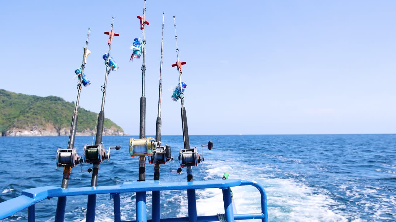 A boat with fishing rods cruises through Phuket's clear blue waters, capturing the serene beauty of the sea