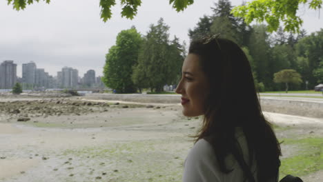 mujer joven y atractiva admirando el horizonte de vancouver al otro lado del agua
