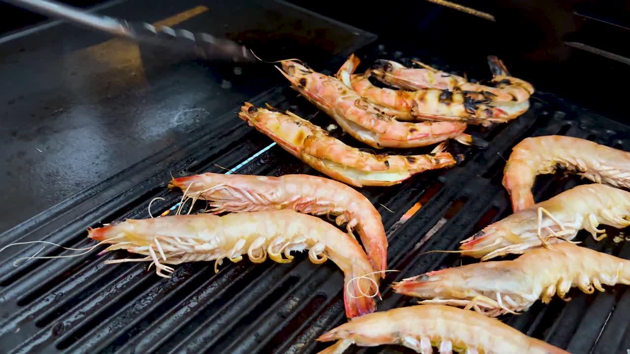 Prawns being grilled with tongs on barbecue