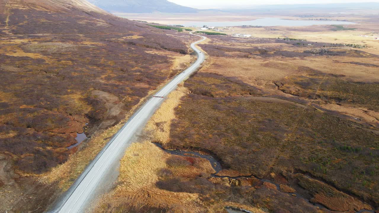 impresionante imagen aérea de un coche conduciendo por una larga carretera a través de un hermoso paisaje islandés