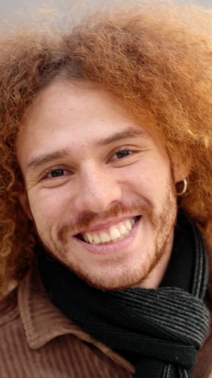 Alternative young man with curly hair smiling at camera