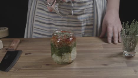 add oil to a glass container with ingredients to prepare argentine chimichurri sauce for barbecues