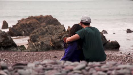 couple sitting on rocky seashore